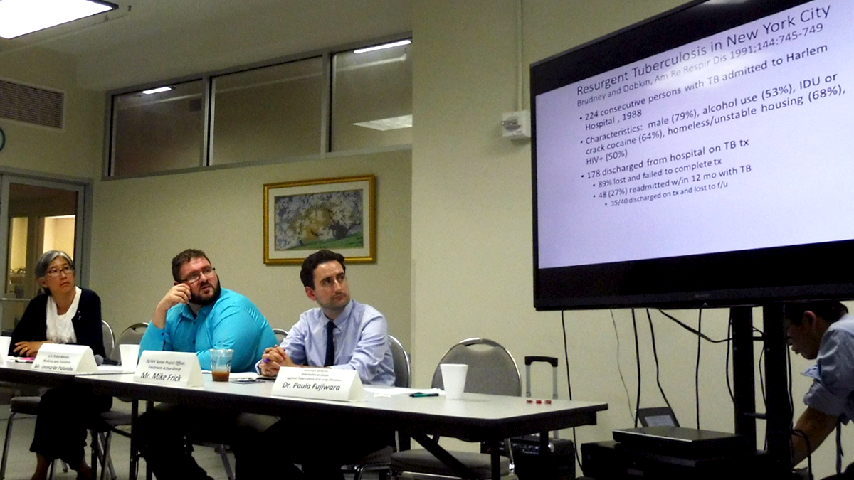 Picture of three people at a table, looking at a screen that says "resurgent tuberculosis in New York City" the man on the right is TAG's Mike Frick