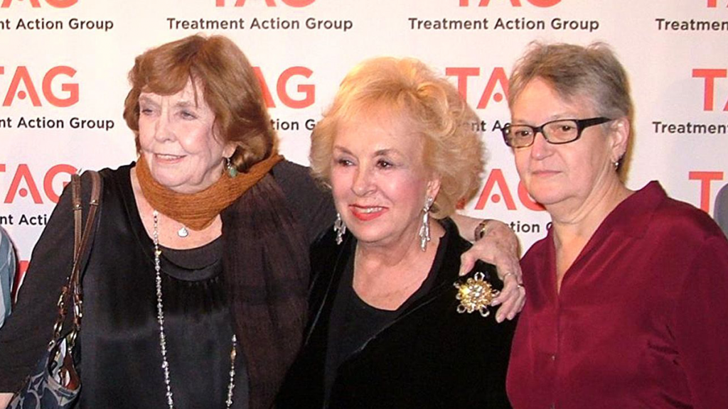 Three Older White Women Posing In Front Of TAG Step And Repeat