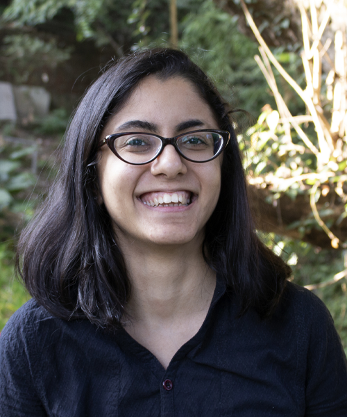 photo of Bakul Piplani: woman smiling with dark hair and glasses, wearing a black or dark blue shirt with buttons