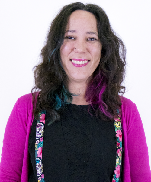 Photo of Laia Ruiz Mingote: smiling woman, longish dark hair, wearing a black shirt under a bright purple sweater (her lipstick matches her sweater perfectly!)