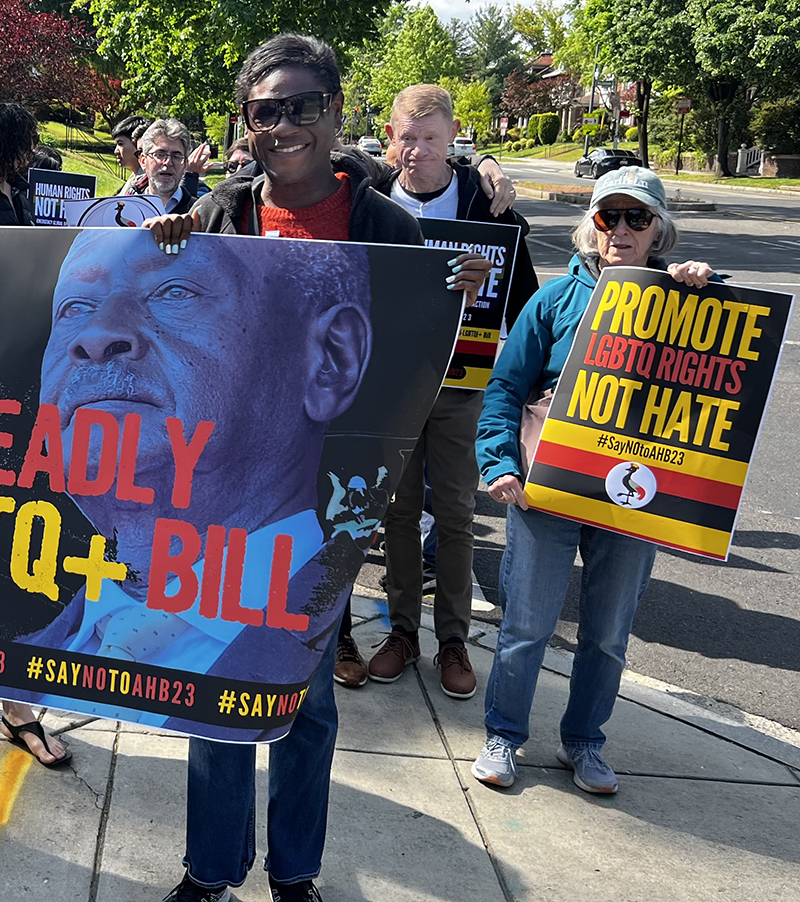 Black woman in foreground holding a protest sign, in a crowd of others with anti-hate signs