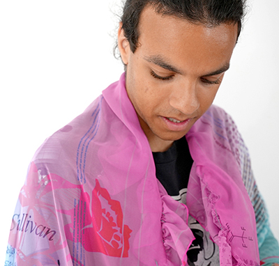 young man modeling the shawl that's part of the 2023 Limited Art Edition by Ivy Kwan Arce